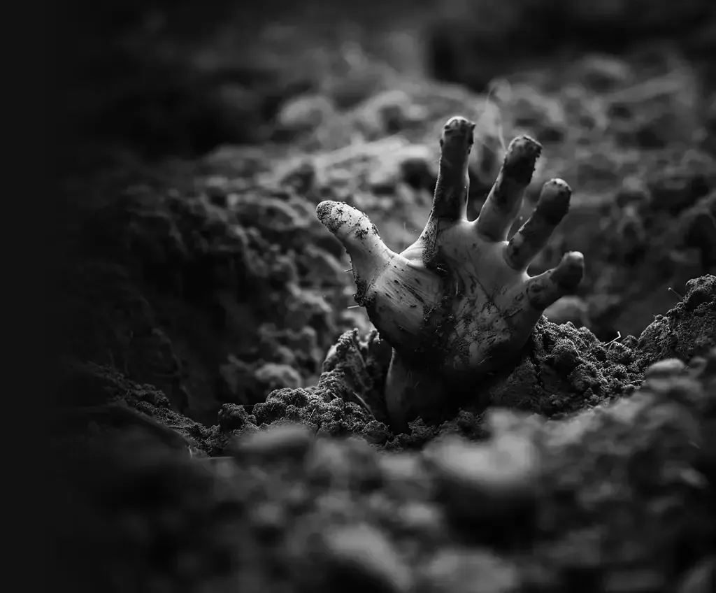 A hand pushing up through grave soil, from the Buried Alive artwork