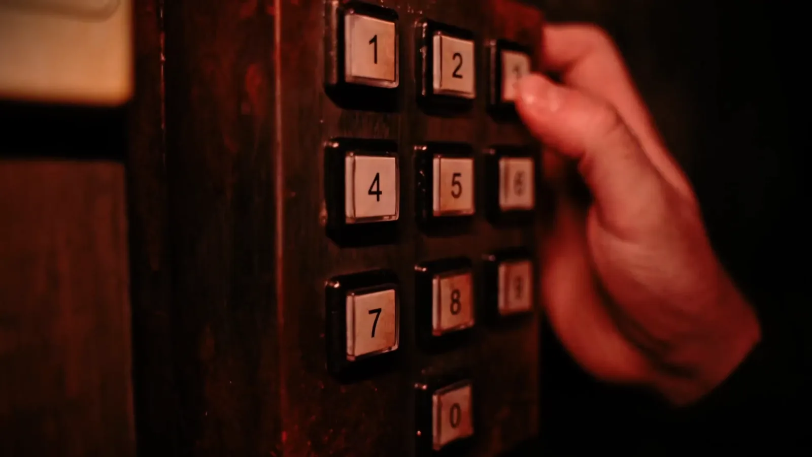 A hand pressing a numbered keypad set into the timber of a Buried Alive coffin