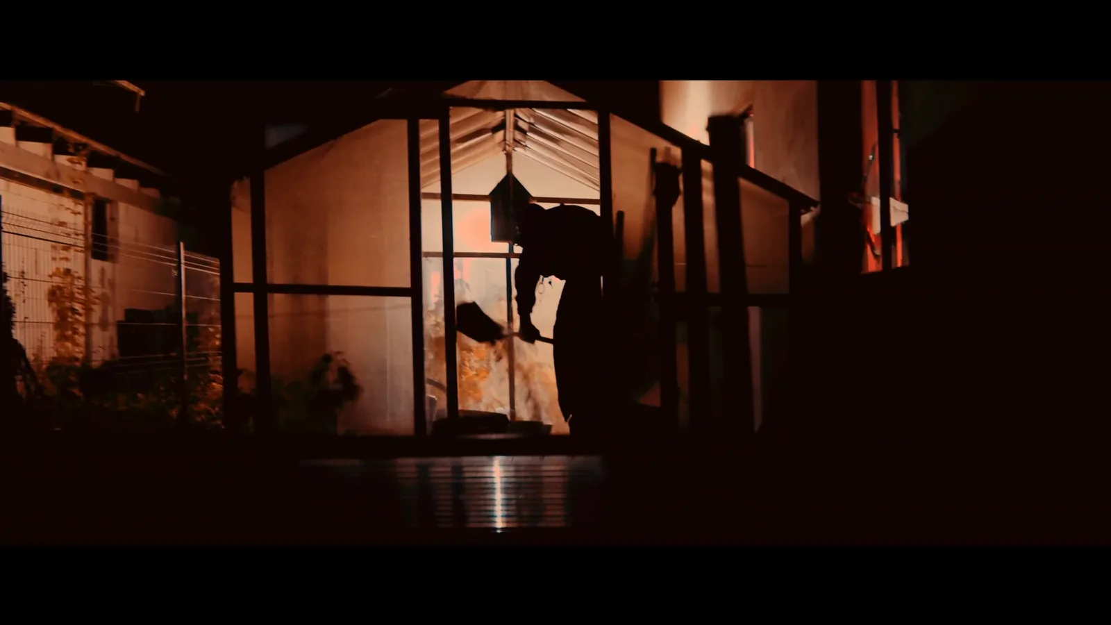 The silhouette of a figure with a shovel in a lit doorway, from the Buried Alive film